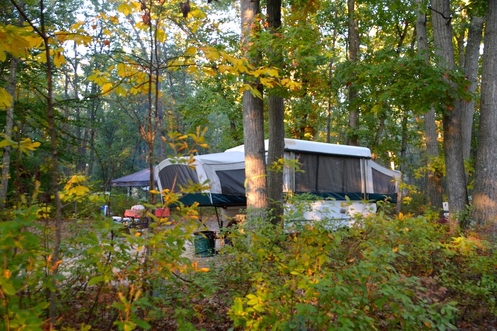 A pop up trailer set up camp in rustic setting